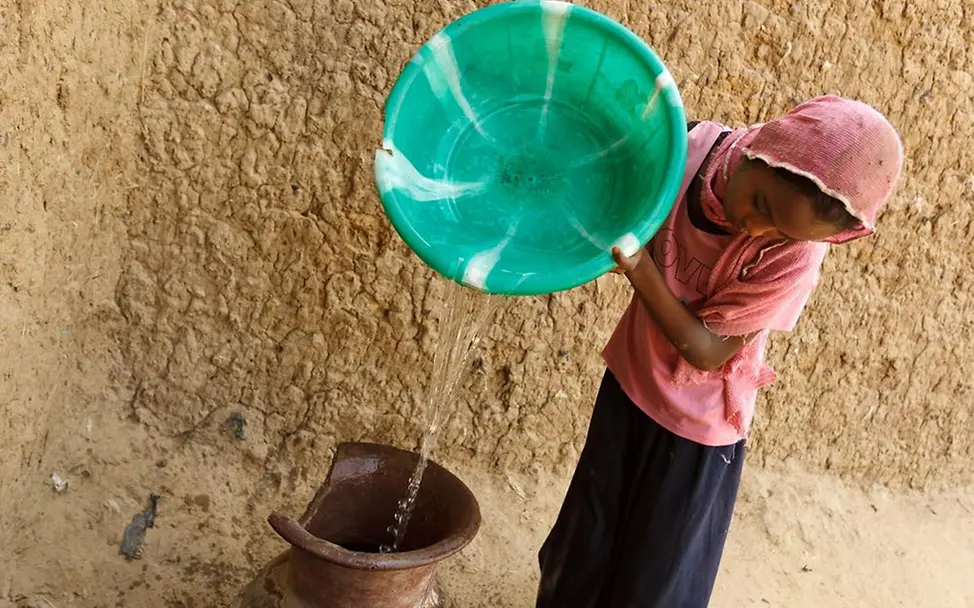 Tschad: Die 10-jährige Aruma gießt sauberes Trinkwasser, das sie gerade vom Brunnen geholt hat, in ein Tongefäß. Tschad Wasser