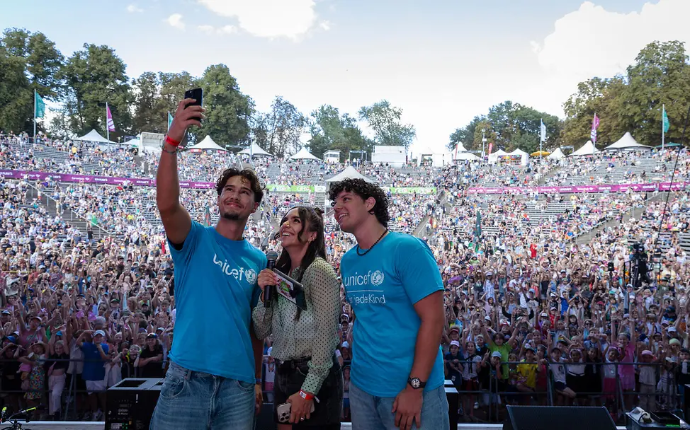 Die Mitglieder des UNICEF-JuniorBeirat, Benedikt (l.) und Donat (r.), gemeinsam mit Moderatorin Jess auf der Bühne. Tobias Eineder / GEOlino