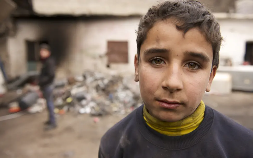 Ahmed aus Syrien: Keine Zeit für Schule mehr | © UNICEF/Noorani Der 14-jährige Ahmed steht vor der Recycling-Anlage. Sein Blick zeigt wie anstrengend die Arbeit für ihn ist.
