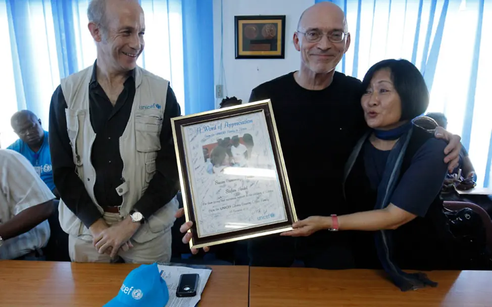 Sheldon Yett, Leiter von UNICEF Liberia, verleiht den Findels eine Urkunde | © UNICEF Liberia/A. Jallonzo Reisetagebuch Liberia: Sheldon Yett, Leiter von UNICEF Liberia mit Ehepaar Findel