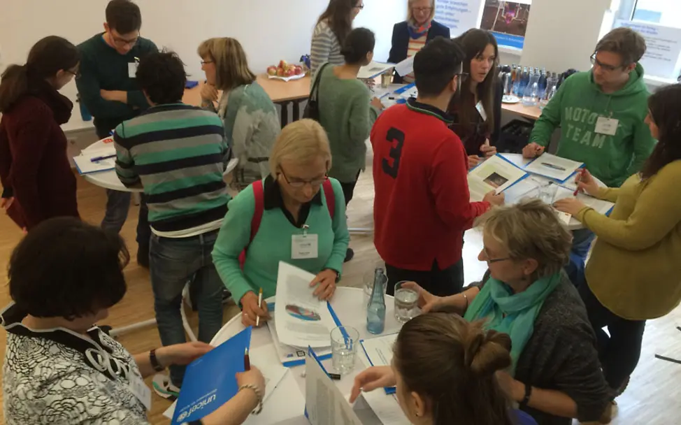 Ehrenamtliche inspizieren die neuen Tagungsmappen