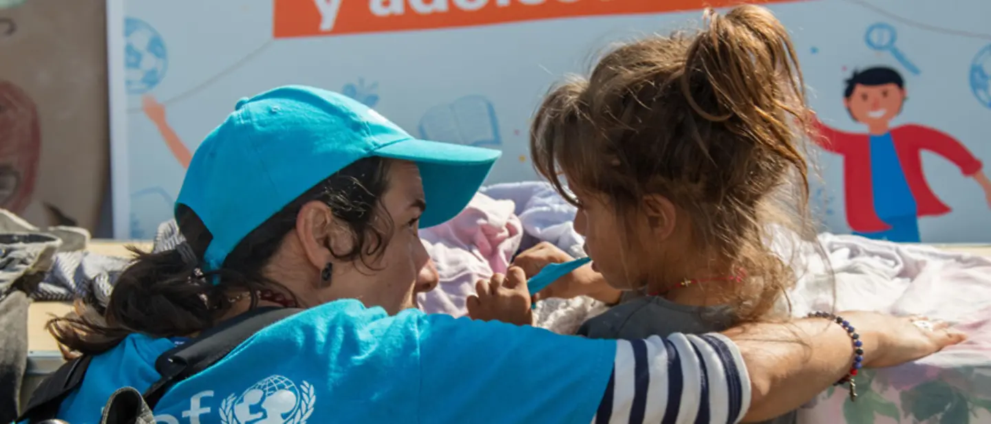UNICEF-Helfer sind weltweit zur Stelle, um Kinder vor Gewalt und Missbrauch zu schützen | © UNICEF/Kelly UNICEF-Helferin spricht mit einem Mädchen, das gerade seine Zähne putzt.