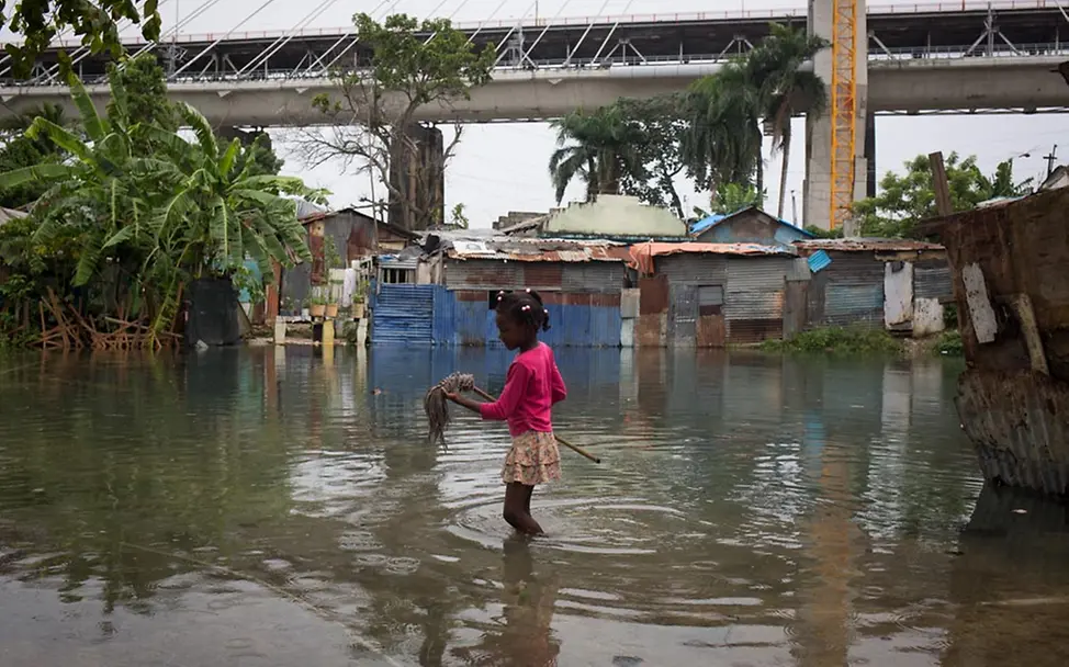 Hurrikan Matthew: Ein kleines Mädchen steht inmitten ihrer überfluteten Nachbarschaft. | © UNICEF/Afonso, Diari Hurrikan Matthew: Ein kleines Mädchen steht knietief im Wasser - inmitten ihrer Nachbarschaft in Santo Domingo.