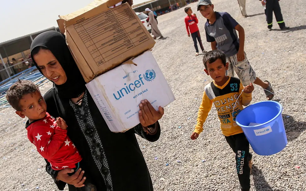 Irak: Familien tragen Hilfsgüter - Das Versorgungspaket beinhaltet Notfallnahrung, Wasser und Hygieneartikel.