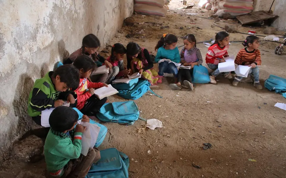 Kinder sitzen auf dem Boden im Kreis zusammen und lernen gemeinsam.