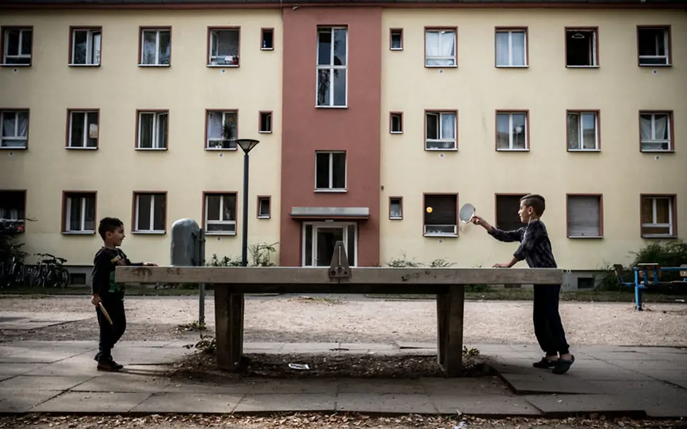 Geschwister beim Tischtennisspielen im Hof einer Flüchtlingsunterkunft | © UNICEF/Ashley Gilbertson UNICEF-Studie Flüchtlingskinder: Geschwister beim Tischtennisspielen im Hof einer Flüchtlingsunterkunft