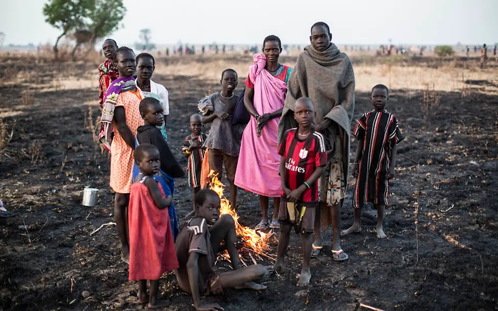 Viele Familien im Südsudan können ihre Felder nicht mehr bestellen | © UNICEF/Siegfried Modola Südsudan: Eine Gruppe steht um ein Lagerfeuer