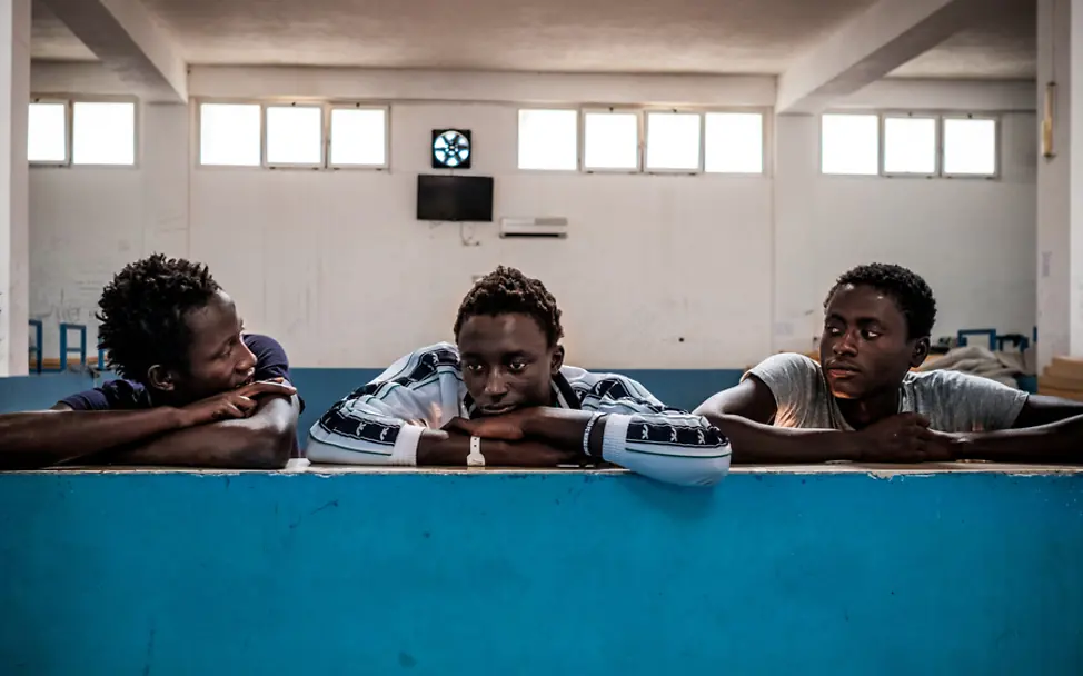 Die drei jungen Männer aus Gambia sind nach Italien geflüchtet | © UNICEF/Gilbertson UNICEF-Report Harrowing Journeys: Drei Minderjährige Flüchtlinge lehnen an einer Mauer