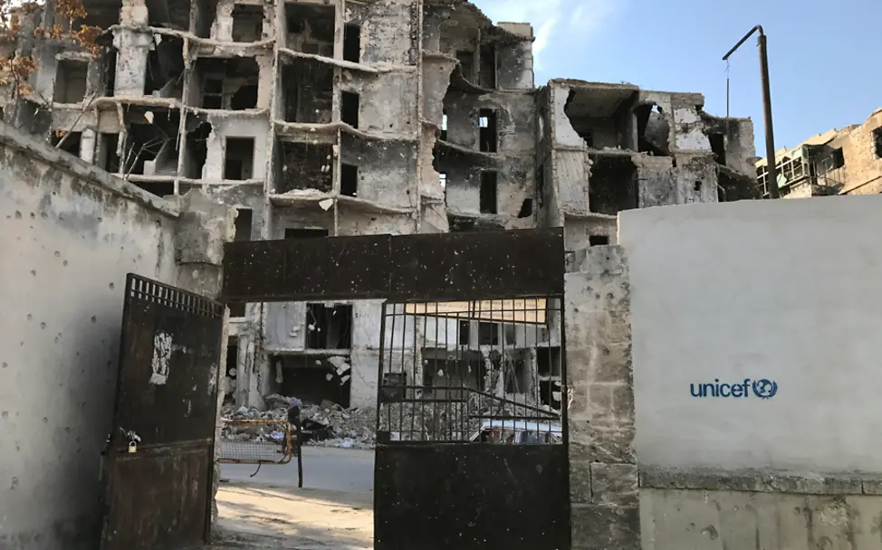 Das UNICEF-Logo hilft dem Schutz dieser Schule | © UNICEF/Ninja Charbonneau Syrien: Ein Blick auf die Trümmer und das UNICEF-Logo im Hof der Ben Yasser Schule