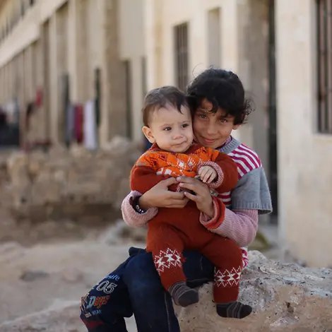 In Syrien leiden die Kinder unter der drohenden Kälte | © UNICEF/Al-Issa Syrien Krieg: Ein Kind in Aleppo hält ein Baby in seinen Armen