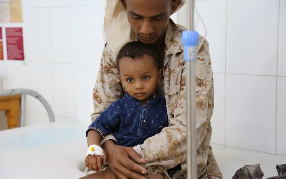 Dieser kleine Junge leidet unter Cholera, wird aber im Krankenhaus behandelt | © UNICEF/Fuad Jemen: Ein kleiner Junge sitzt im Krankenhaus auf dem Schoß seines Vaters