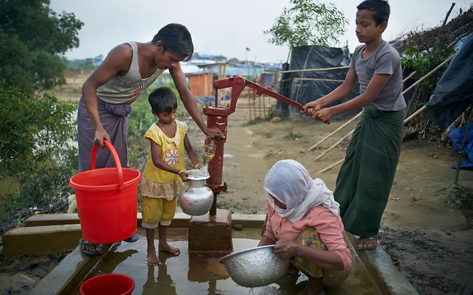 Sauberes Trinkwasser ist überlebenswichtig. | © UNICEF/Noorani Eine Familie in Bangladesch pumpt an einem Brunnen frisches Trinkwasser.