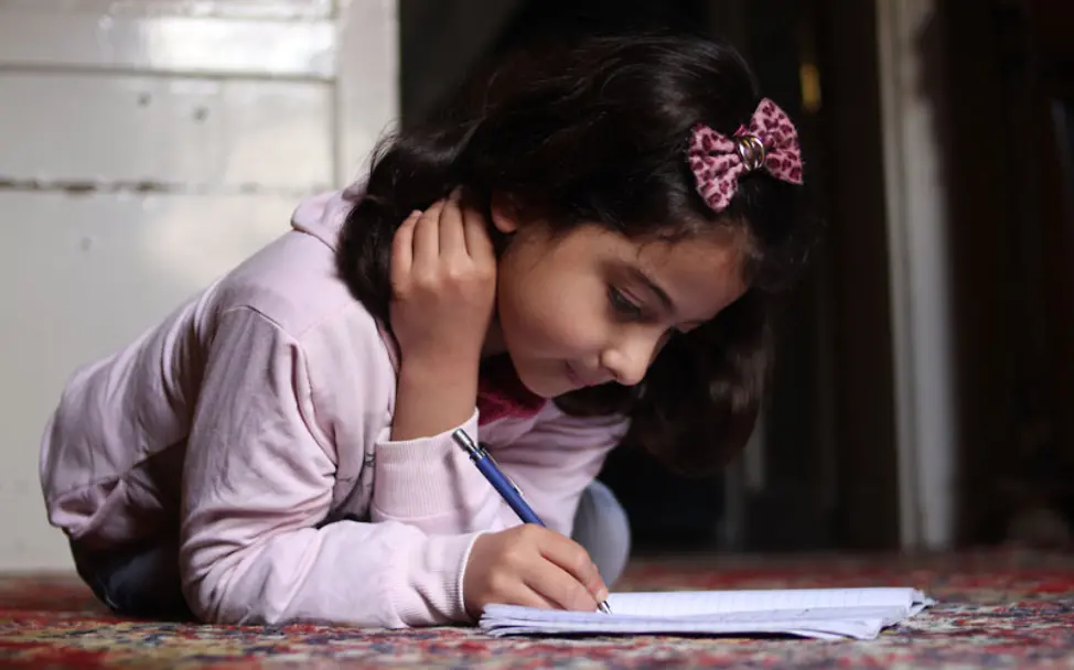 Rama schreibt in einem Brief an Kinder in Deutschland über ihr Leben | © UNICEF/ Khudr Al-Issa Ost Aleppo: Rama schreibt auf dem Boden einen Brief