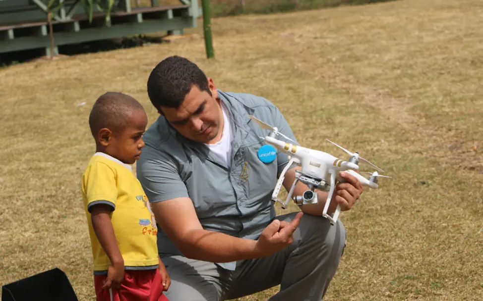 UNICEF-Mitarbeiter zeigt einem neugierigen Kindern in Malawi eine Drohne im Detail. | © UNICEF Pacific/Kaitiple Malawi: Das UNICEF-Innovationsteam zeigt Kindern die neusten Technologien in puncto Drohnen