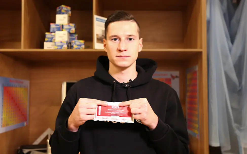Julian Draxler hält die nahrhafte Erdnusspaste in der Hand, die beim Kampf gegen Mangelernährung eingesetzt wird. | © UNICEF/Thomas Ulrich Julian Draxler hält die nahrhafte Erdnusspaste in der Hand.