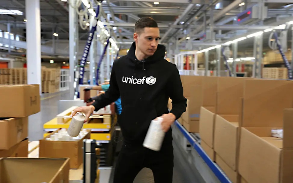 Julian Draxler hat im UNICEF-Logistikzentrum in Kopenhagen Pakete mit Hilfsgütern gepackt. | © UNICEF/Thomas Ulrich Julian Draxler hilft beim Packen von Hilfsgütern im UNICEF-Logistikzentrum in Kopenhagen.