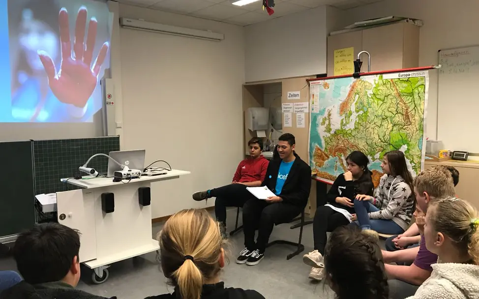 Junior-Teamer Jess Makeba (blaues T-Shirt) bespricht die Aktionen zum Red Hand Day © UNICEF