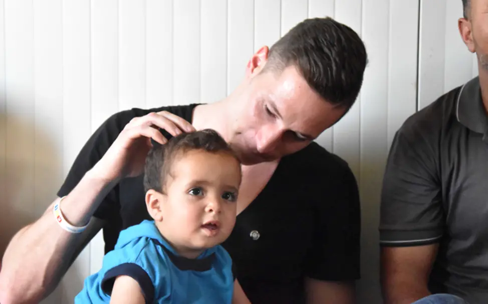 Jordanien: Julian Draxler hält den kleinen Abdullah auf dem Schoß und streichelt ihn.