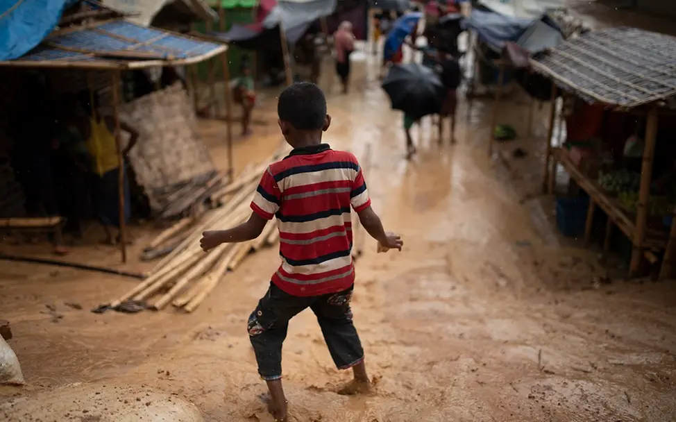 Rohingya in Bangladesch: Die Monsun-Zeit hat begonnen | © UNICEF/Sokol Rohingya Monsun: Junge auf matschigem, überschwemmten Weg im Flüchtlingscamp