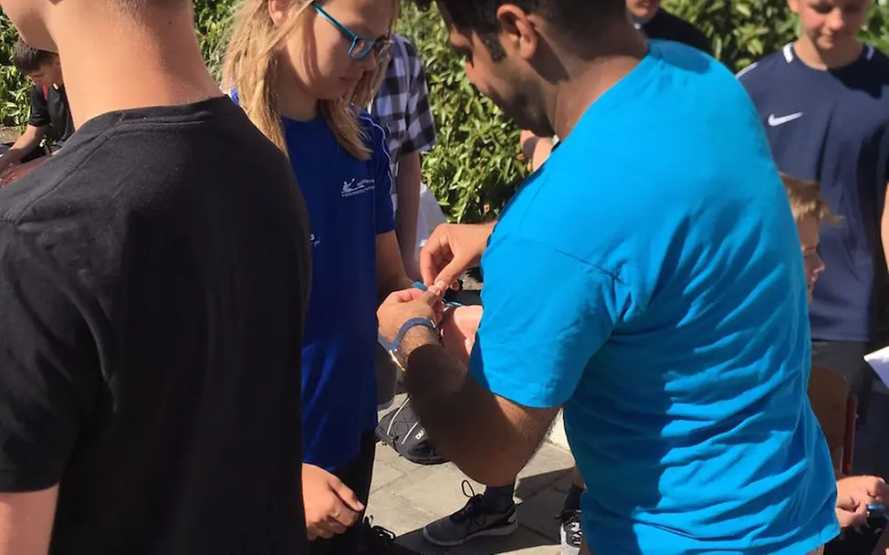 Ehrenamtlicher verteilt Freundschaftsbändchen | © UNICEF Potsdam/Jamil