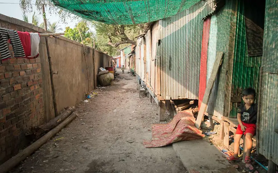 Kinder in Kambodscha sind vielen Gefahren ausgesetzt. | © UNICEF/Llaurado Ein Junge in einer armen Gegend sitzt auf der Stufe der Hütte, in der er lebt.