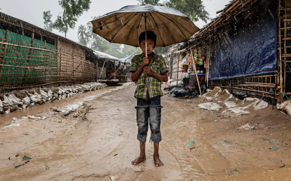 Rohingya: Ein Junge steht im Flüchtlingscamp unter einem Schirm