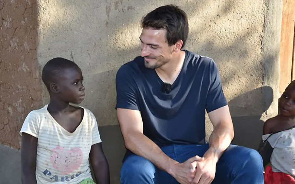 Eine Begegnung mit Veränderung. | © UNICEF/Claudia Berger Mats und Regina sitzen nebeneinander vor einer Mauer.