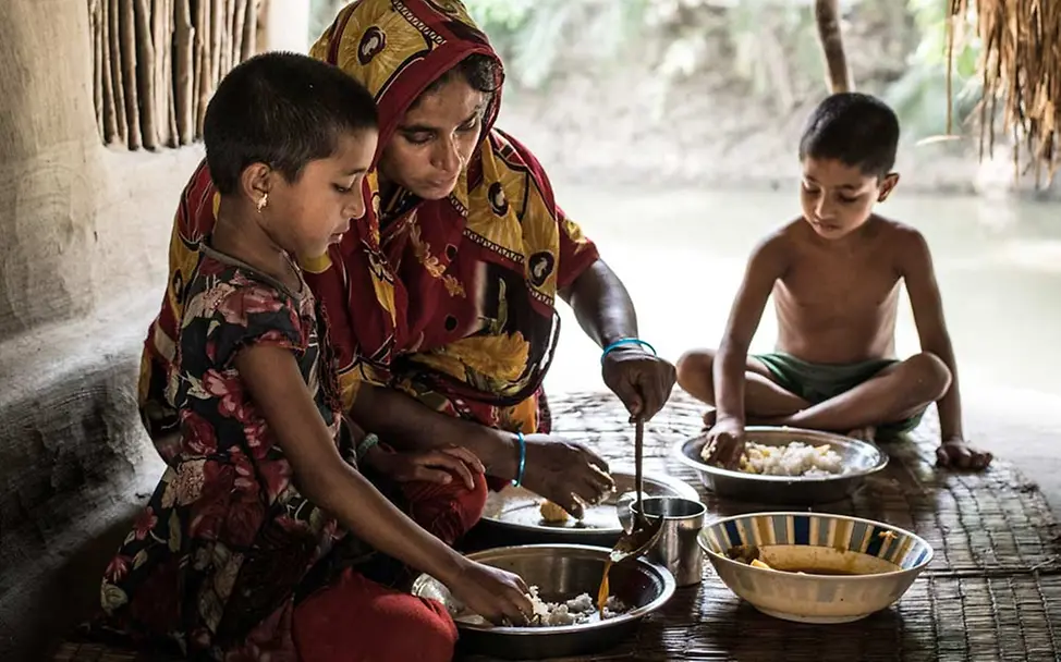 Eine Familie in Bangladesch beim Essen. | © UNICEF/Gilbertson VII Photo Eine Mutter kocht mit wenigen Zutaten ein gesundes Essen.