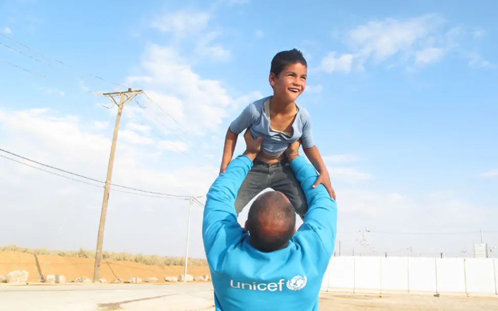 Ein UNICEF-Helfer in Jordanien hebt einen Jungen hoch | © UNICEF/Abimeri Jordanien: Ein UNICEF-Helfer hebt einen Jungen hoch