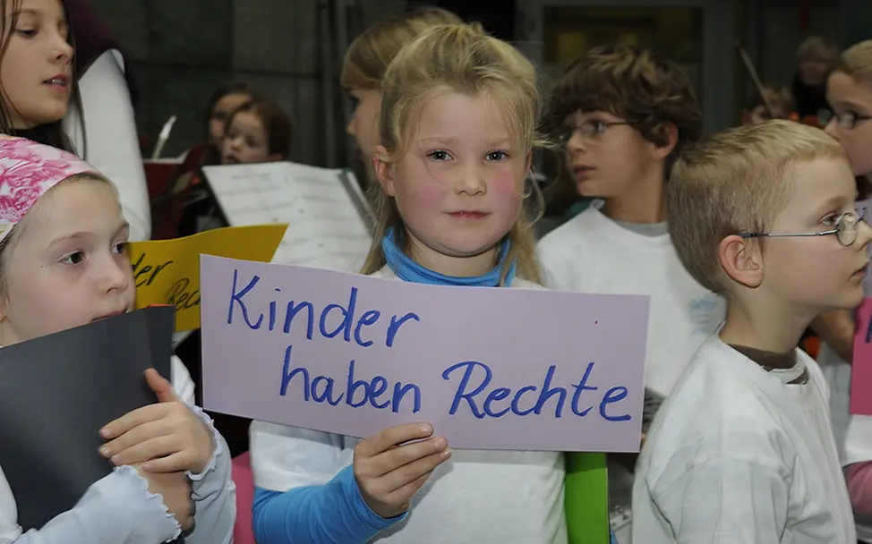 Kinder haben Rechte. | © UNICEF Ein Mädchen hält ein Schild hoch mit der Aufschrift: "Kinder haben Rechte".