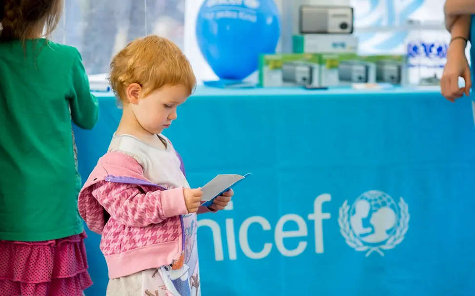 Auf dem Weltkindertagsfest in Köln: Ein Kind schaut sich an einem UNICEF-Infostand einen UNICEF-Flyer an.