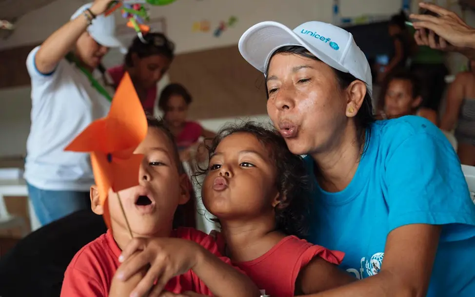 Eine UNICEF-Helferin spielt mit zwei Migranten-Kindern. | © UNICEF/Arcos Basteln und Spielen stehen im Vordergrund in den kinderfreundlichen Zonen.
