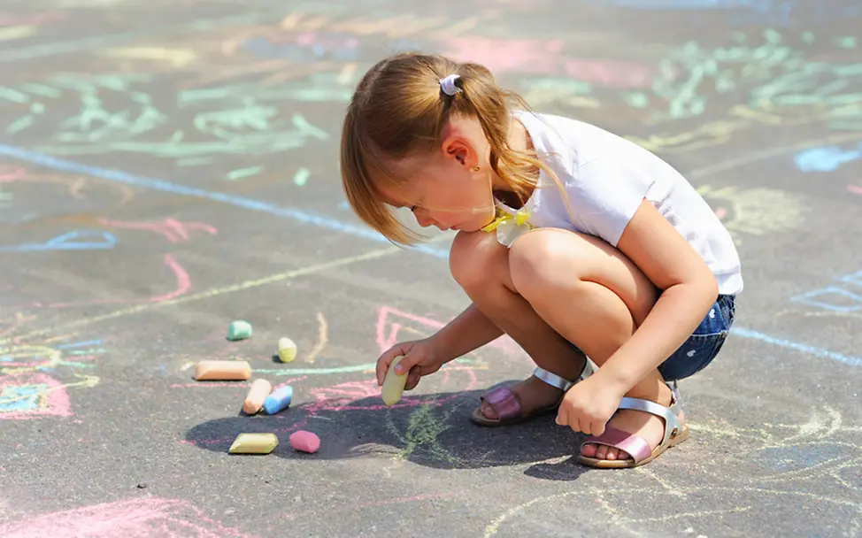 Weltkindertag 2021: Ein Mädchen malt ein Kreidebild