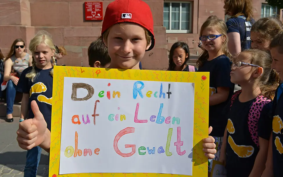 Jedes Kind hat das Recht auf ein Leben ohne Gewalt. | © UNICEF/Hyou Vielz Deutschland: Ein Junge hält ein Plakat für das Recht auf ein Leben ohne Gewalt.