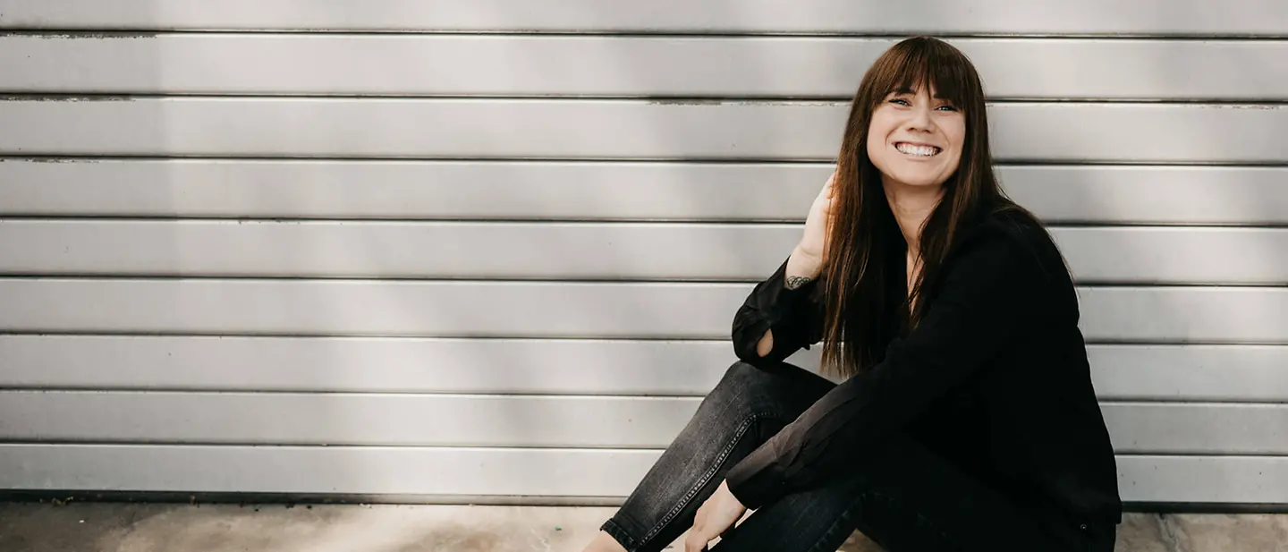 Louisa Dellert spendet Zukunft | © Laura Hoffmann Louisa Dellert sitzt vor einer Holzwand