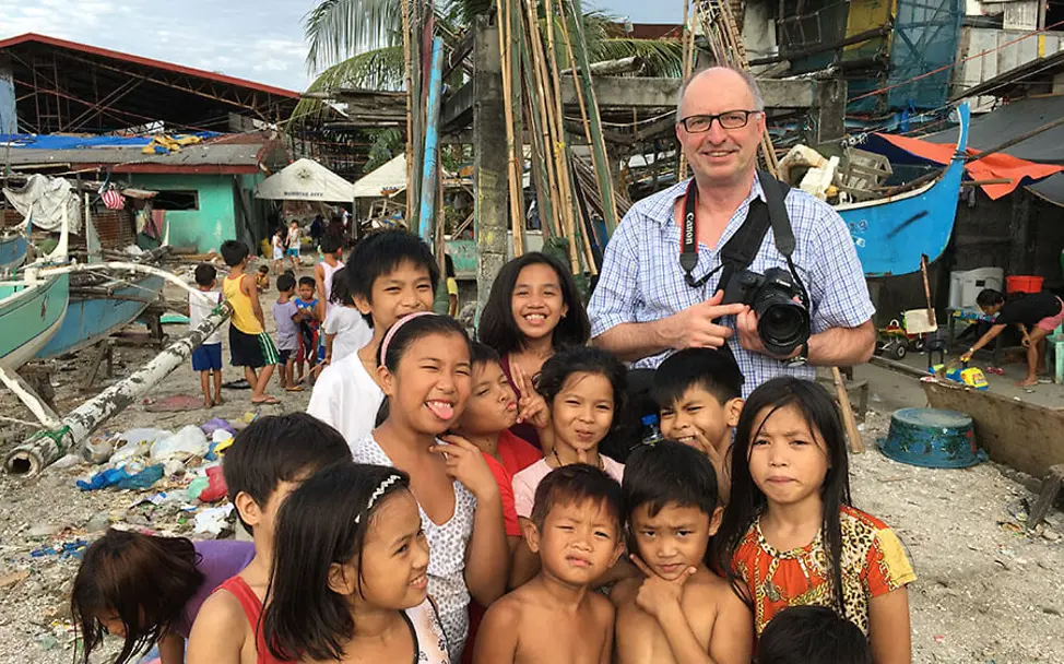 Der Fotograf begleitet die Kinder in der Manila Bucht mit seiner Kamera. | © Hartmut Schwarzbach Philippinen: Fotograf Hartmut Schwarzbach mit einer Gruppe von Kindern in der Manila Bucht.