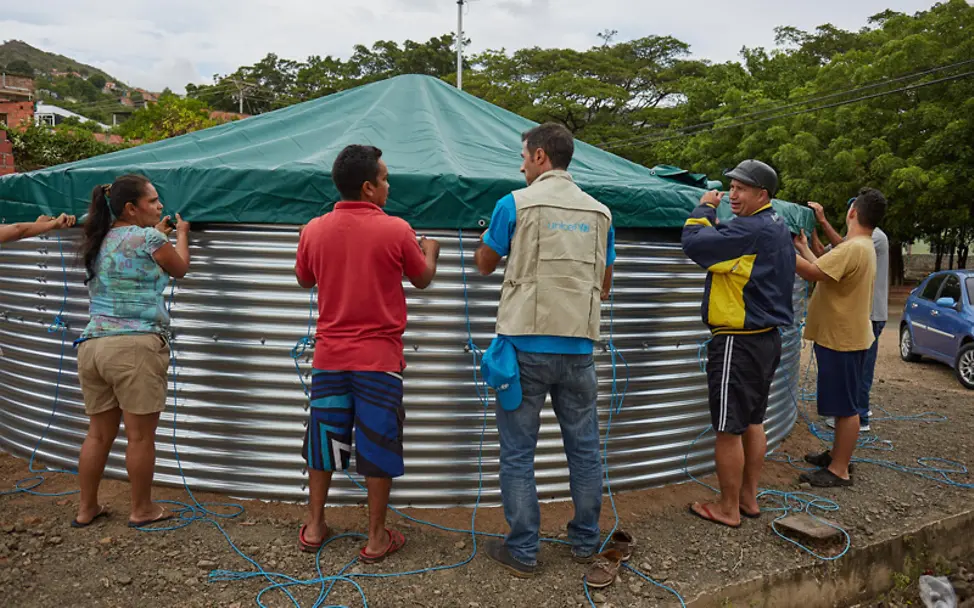 UNICEF-Mitarbeiter und Helfer stellen in Venezuela einen Tank für Trinkwasser auf | © UNICEF/Montico Venezuela: UNICEF-Mitarbeiter und Helfer stellen einen Tank für Trinkwasser auf