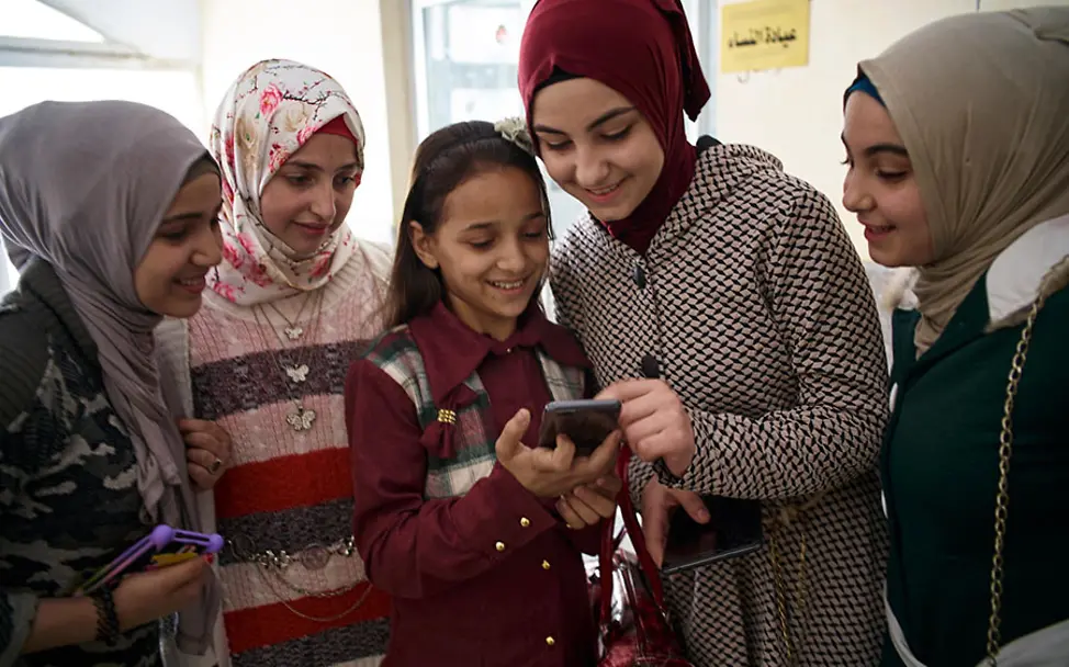 Jugendliche nutzen das Internet, um sich auszutauschen. | © UNICEF/Noorani Syrien: Eine Gruppe von Mädchen haben sich um ein Smartphone versammelt.