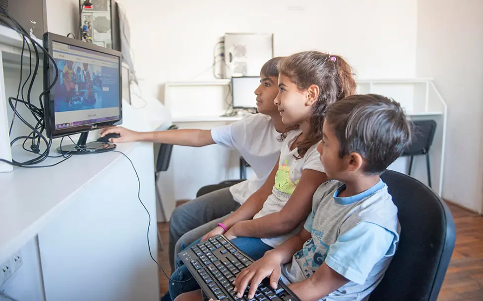 Flüchltingskinder nutzen das Internet in einem UNICEF-Zentrum. | © UNICEF/Pancic Belgrad: Drei Kinder durchstöbern das Internet in einem UNICEF-Zentrum.