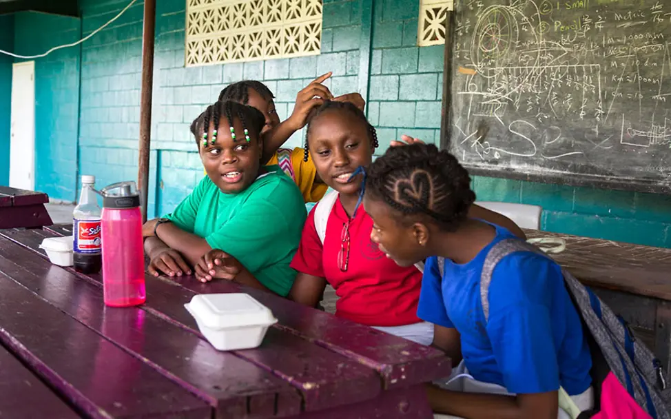 In der Pause flechten sich die Mädchen die Haare. | © UNICEF/LeMoyne Schule in Antigua: Mädchen flechten sich die Haare.