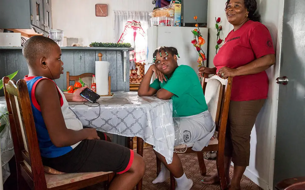 Die Geschwister James und Jerrene mit ihrer Mutter. | © UNICEF/LeMoyne Häuschen in Saint John's: Die Familie zusammen in der Küche.