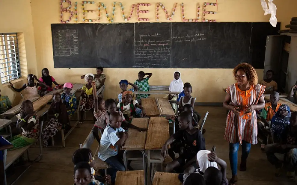 Die Lehrerin steht in mitten der Klassengemeinschaft. | © UNICEF/Bindra Schule in Dori: Die Lehrerin läuft durch die Klasse.