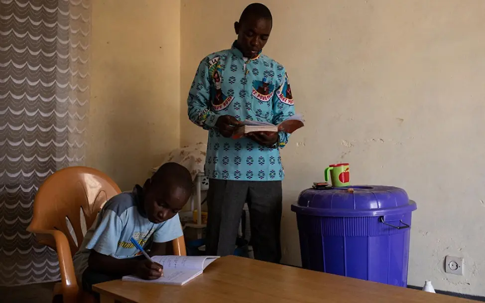 Der große Bruder unterstützt Daniel bei den Hausaufgaben. | © UNICEF/Bindra Unterricht in Dori: Bruder hilft Daniel mit den Hausaufgaben.