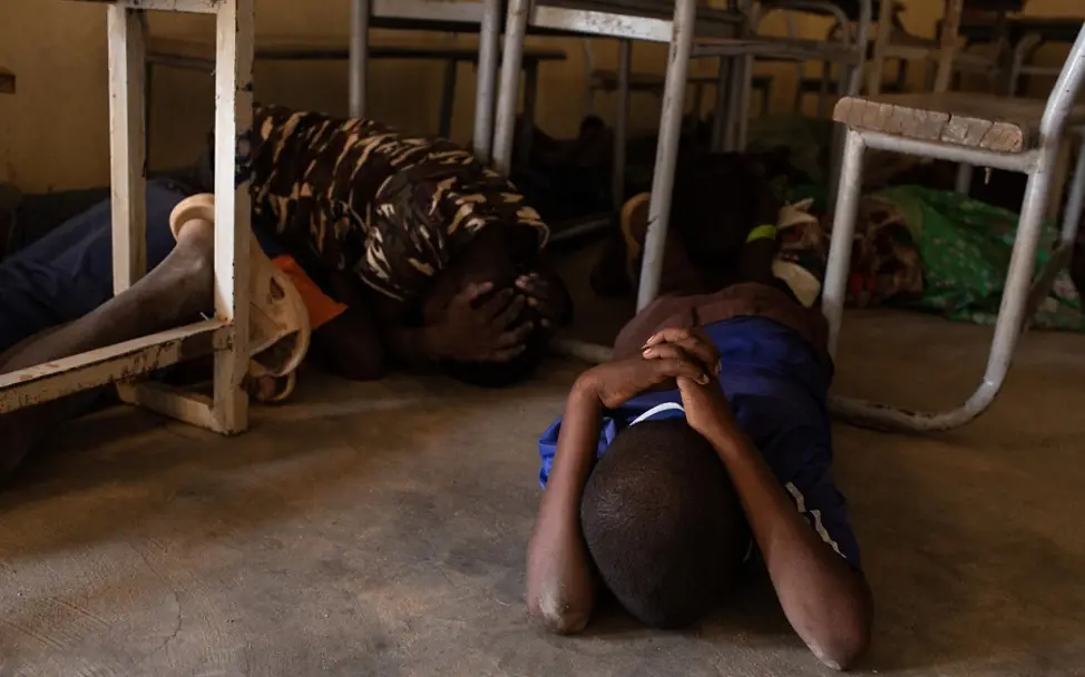 Die Kinder halten sich schützend die Hände über den Kopf. | © UNICEF/Bindra Notfallübung in der Schule: Kinder liegen auf dem Boden.
