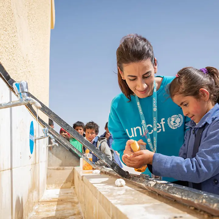 UNICEF-Helferin zeigt einem Mädchen in Jordanien, wie Händewaschen richtig geht.