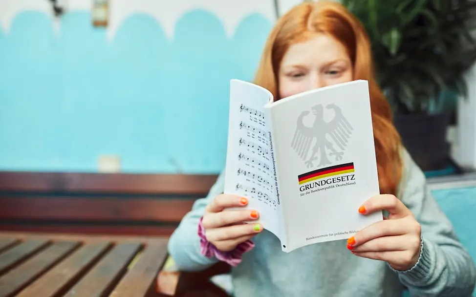 Appell an die Politik: Kinderrechte ins Grundgesetz – jetzt! | © UNICEF/Sebastian Bänsch Kinderrechte ins Grundgesetz: Ein Mädchen liest im deutschen Grundgesetz