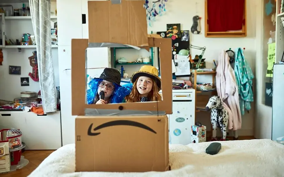 Ein Karton wird zum Kasperle-Theater umfunktioniert. | © UNICEF/Bänsch Spielende Kinder: Zwei Mädchen spielen Kasperle-Theater.