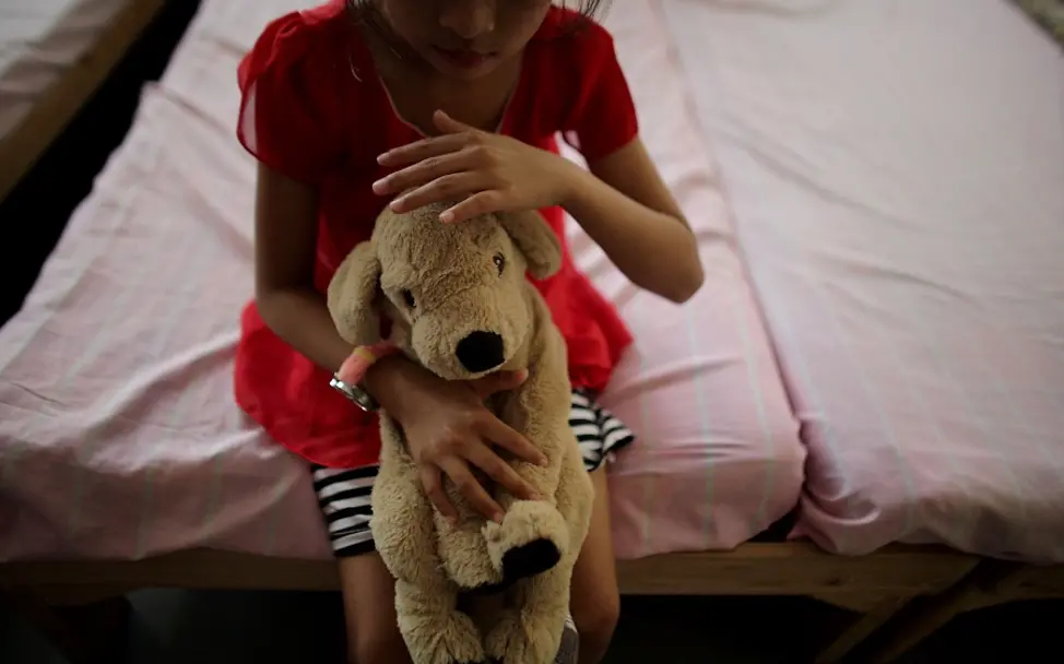 Jedes Kind hat ein Recht darauf, ohne Gewalt groß zu werden. | © UNICEF/Estey Ein Kind sitzt mit einem Teddy auf einem Bett.