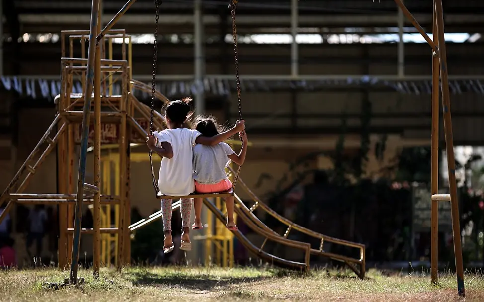 Um Kinder zu schützen, muss die ganze Gesellschaft für Kinderrechtsverletzungen sensibilisiert werden. | © UNICEF/Estey Zwei Kinder sitzen auf einer Schaukel.