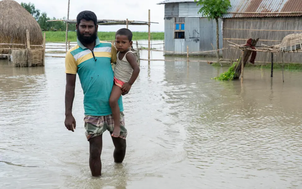 Monsun 2020 in Bangladesch: Ein Vater steht mit seinem Kind auf dem Arm im Hochwasser | © UNICEF/Chakma Monsun 2020 in Bangladesch: Ein Vater steht mit seinem Kind auf dem Arm im Hochwasser